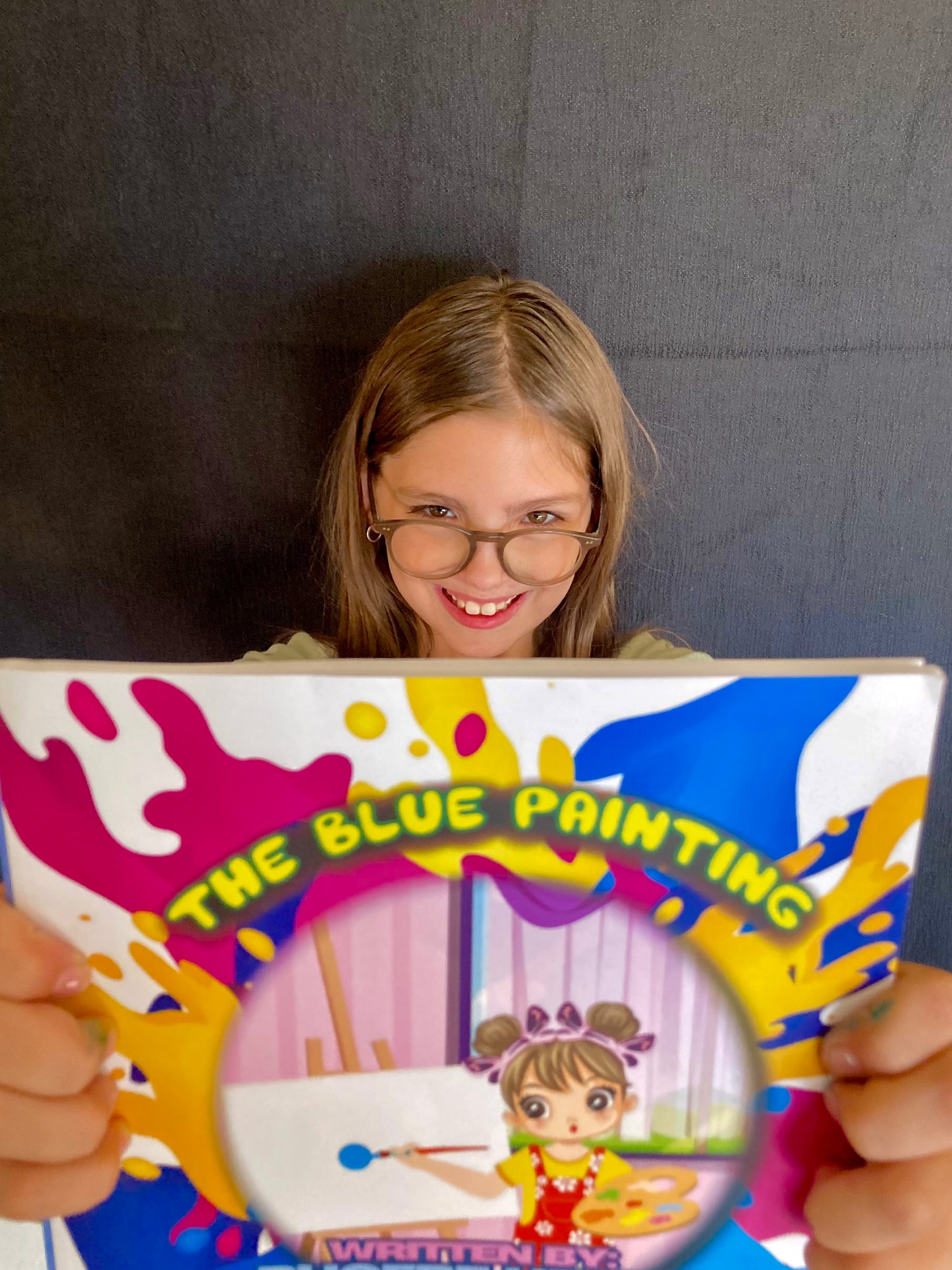 Children's book coda author holding The Blue Painting book with colorful splash cover