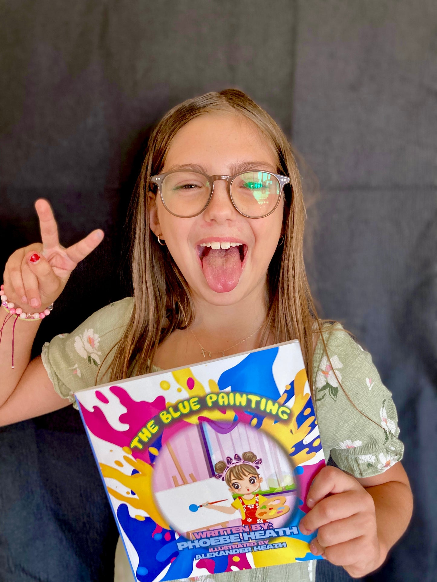 Children's book coda author holding The Blue Painting book excitedly with playful expression