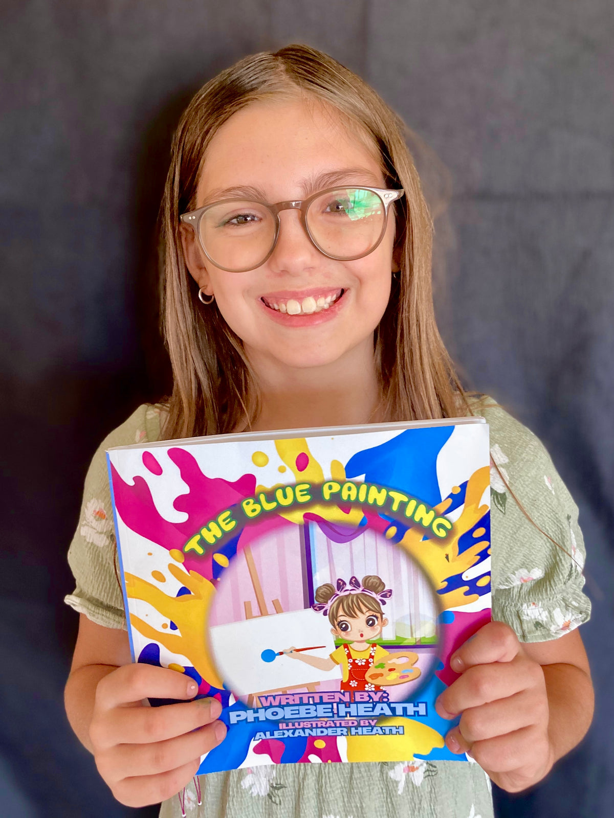 Smiling girl holding a colorful children's book by the children's book coda author