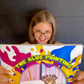 Children's book coda author holding The Blue Painting book with colorful splash cover