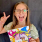 Children's book coda author holding The Blue Painting book excitedly with playful expression