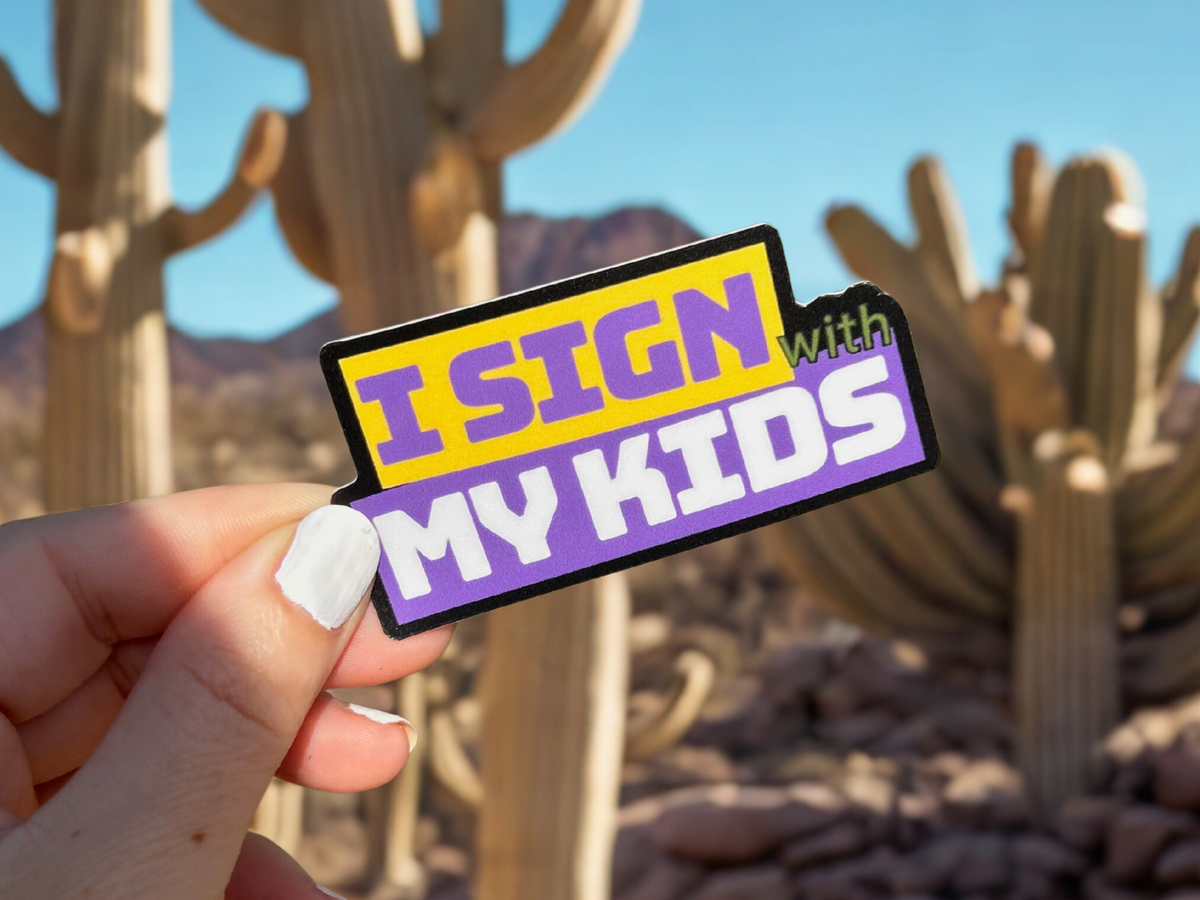 Colorful I sign with my kids sticker held against a desert background featuring cacti