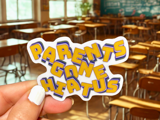 Parents Gone Hiatus sticker in vibrant colors held in a classroom setting with desks
