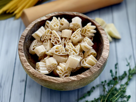 Wooden bowl of uncooked handshaped pasta next to rolling pin and herbs 16 oz 1-3-5 American Sign Language Handshaped Pasta.