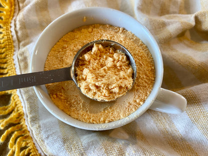 Close-up of mac and cheese seasoning jar with measuring scoop showing delicious cheese blend