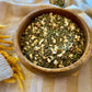 Basil pesto seasoning with dried garlic mix in a wooden bowl on a textured yellow and white cloth